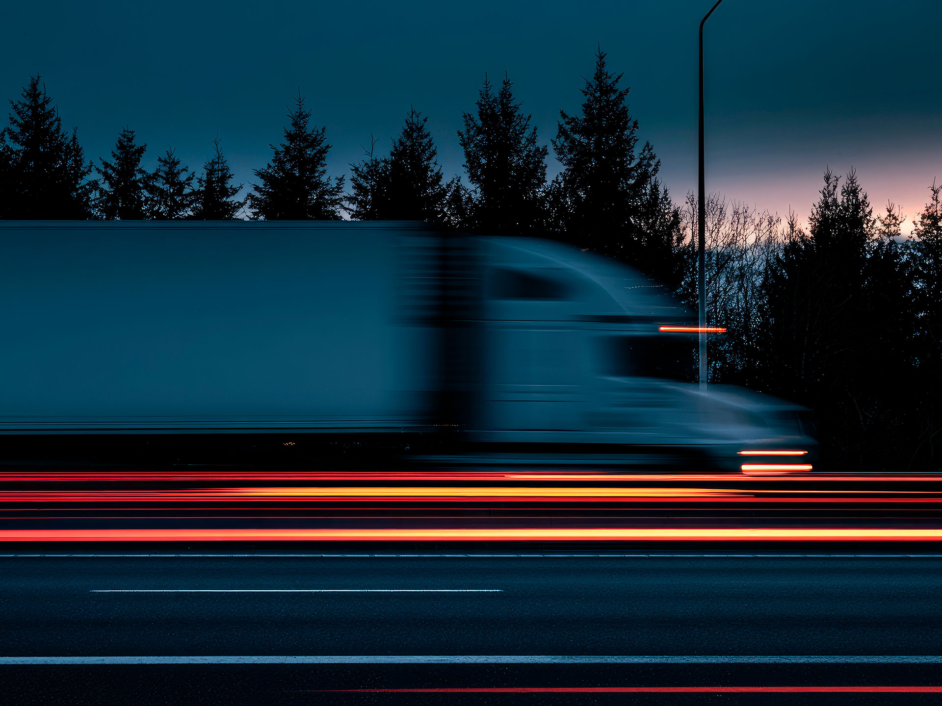 Camión circulando de noche por autovía con estelas de luz